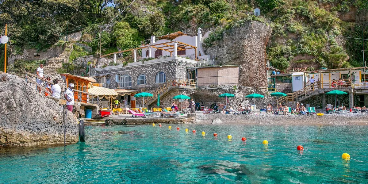 Small sandy-pebble beach and sunbeds by Roman ruins at Bagni di Tiberio, near Marina Grande