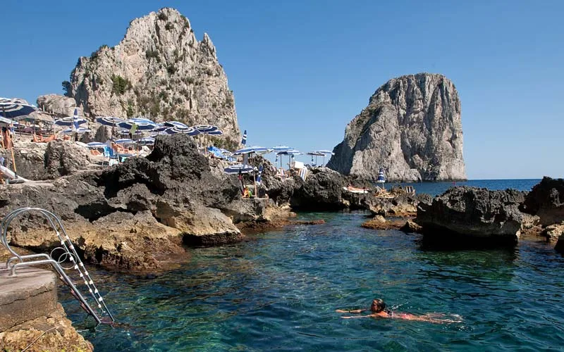 Sunbeds on the rocks below the Faraglioni sea stacks at La Fontelina, Faraglioni