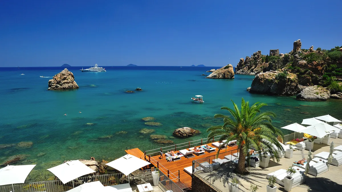 King-size daybeds on terraces above Caldura bay at Le Calette Reef Club, Cefalù