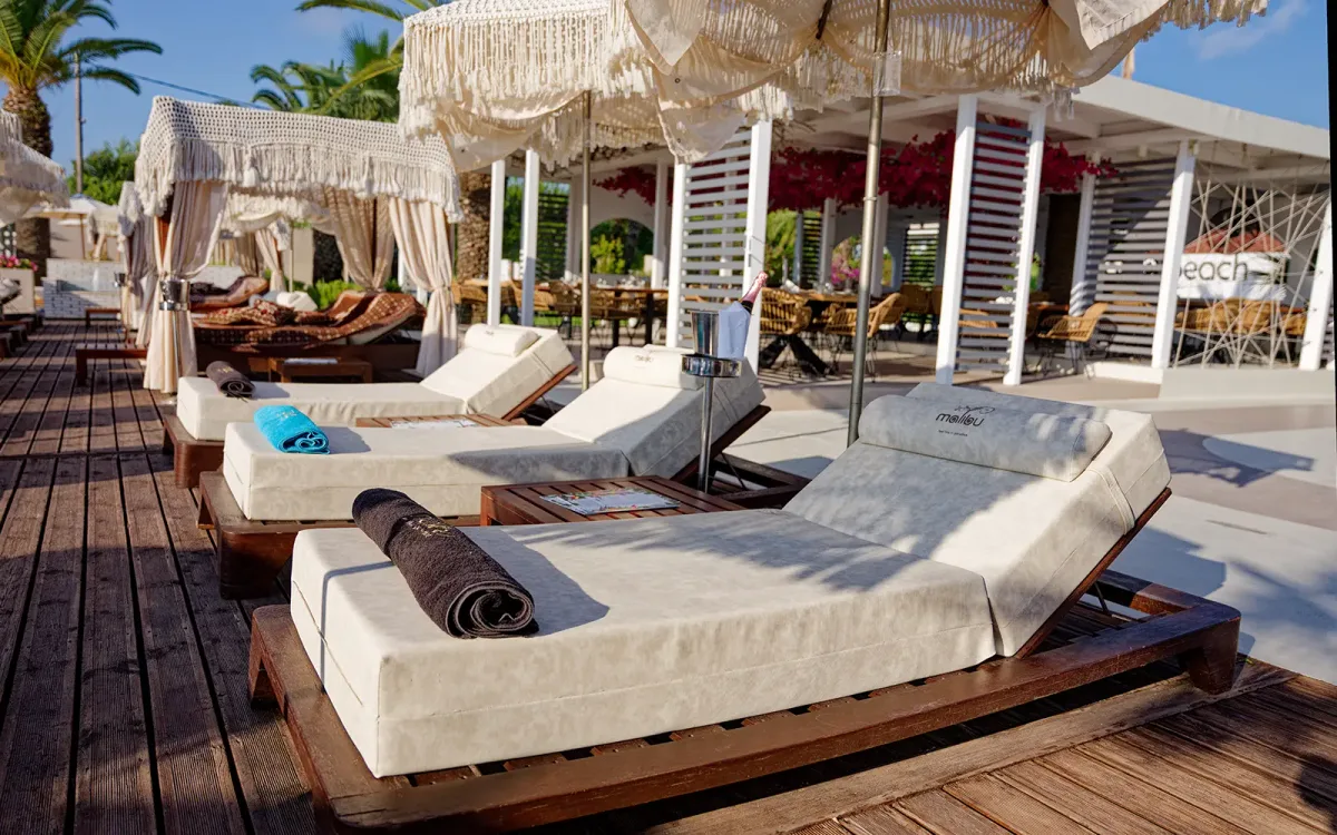 Poolside sunbeds and beach volleyball at Malibu Summer, Dassia Beach