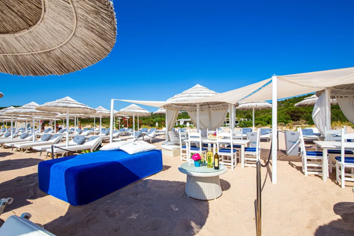 Quiet sunbeds between Mediterranean scrub and clear water at White Beach Club, Liscia Ruja