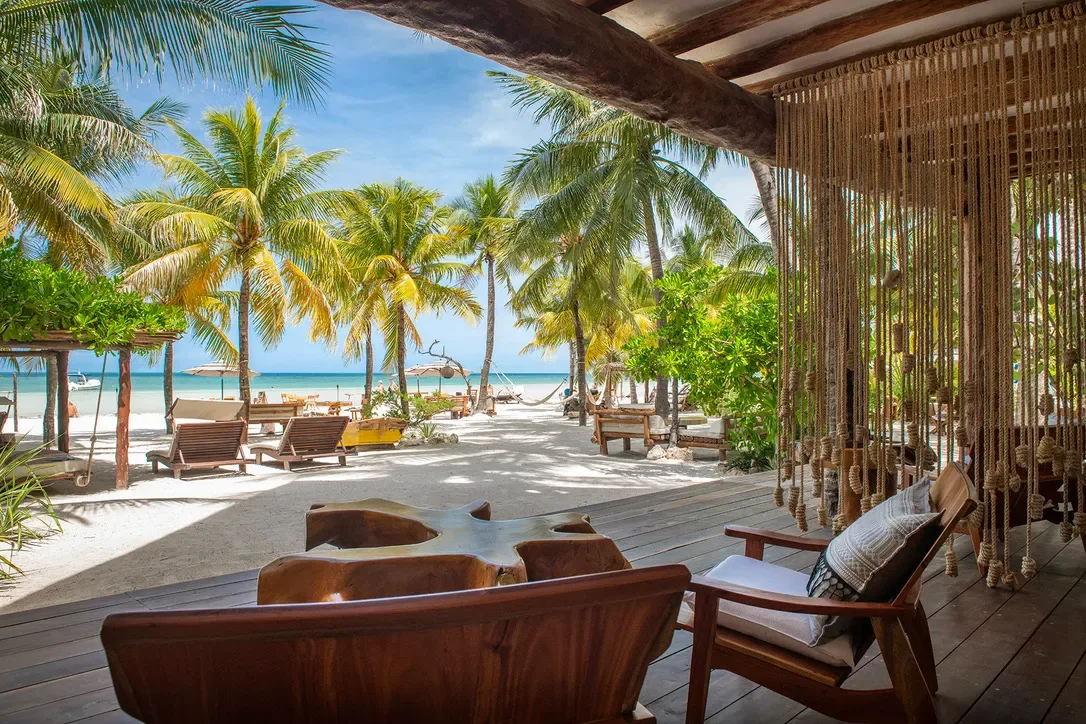 Palm-shaded swing beds and hammocks on the sand at Mawimbi Beach Club, Holbox centro