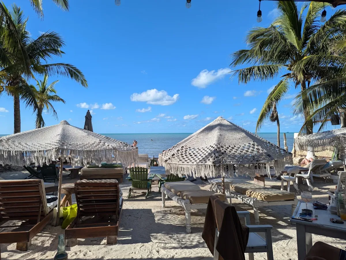 White loungers under macrame umbrellas at MARUVA Beach Club, Playa Holbox