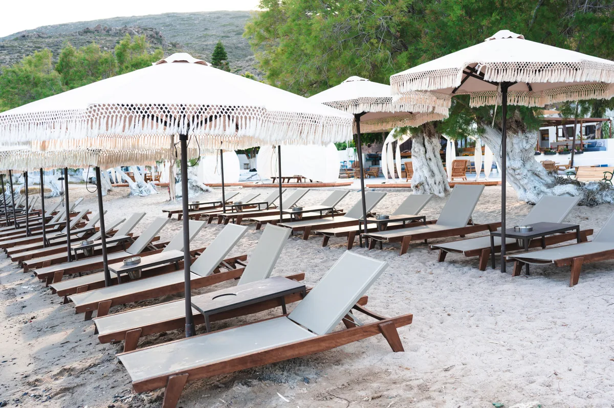 Private beach with sunbeds and straw umbrellas at Buddha-Bar Beach Milos, Lagkadas Beach