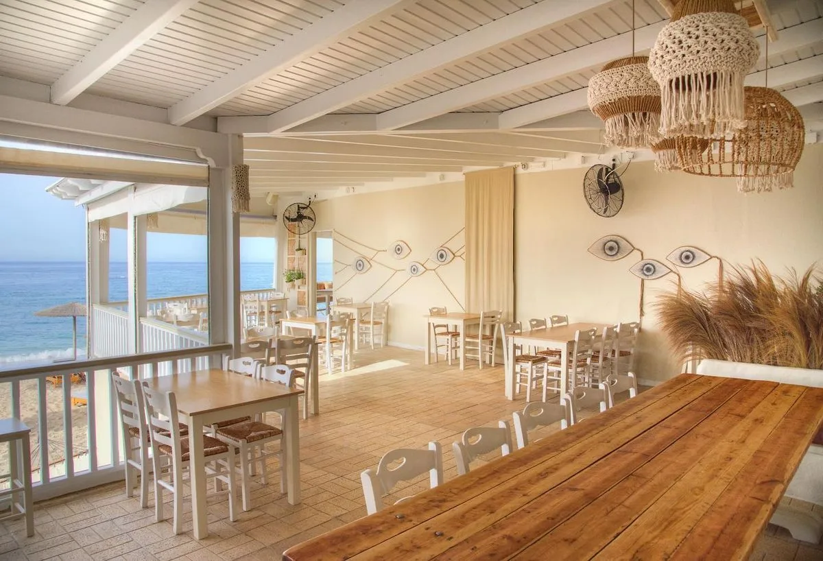 Volcanic-sand cooking and beachfront tables at Sirocco, Paliochori Beach