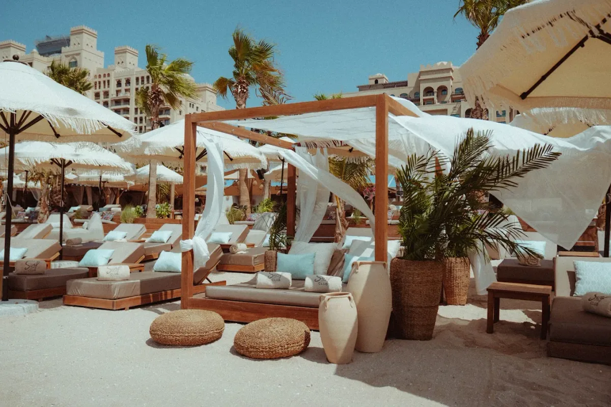 Cabanas and sunbeds facing a west-facing sunset at Surf Club Dubai, Palm West Beach