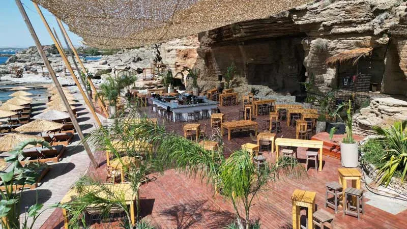 Cave bar and sunbeds on the rocks at Oasis Beach, Kallithea