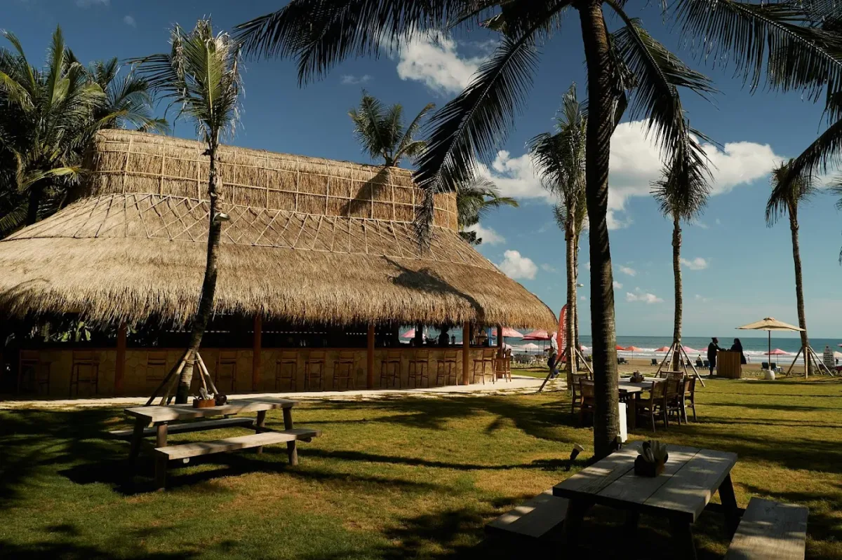 Thatched roof and navy umbrellas over beach seating at Sunset Beach Bali, Seminyak Beach