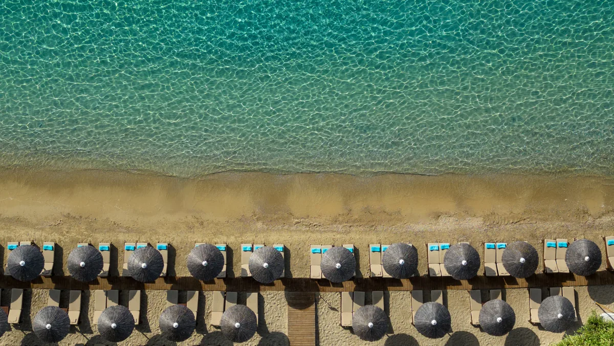 Memory-foam sunbeds under olive trees at Mystique Beach Club, Ampelakia Beach