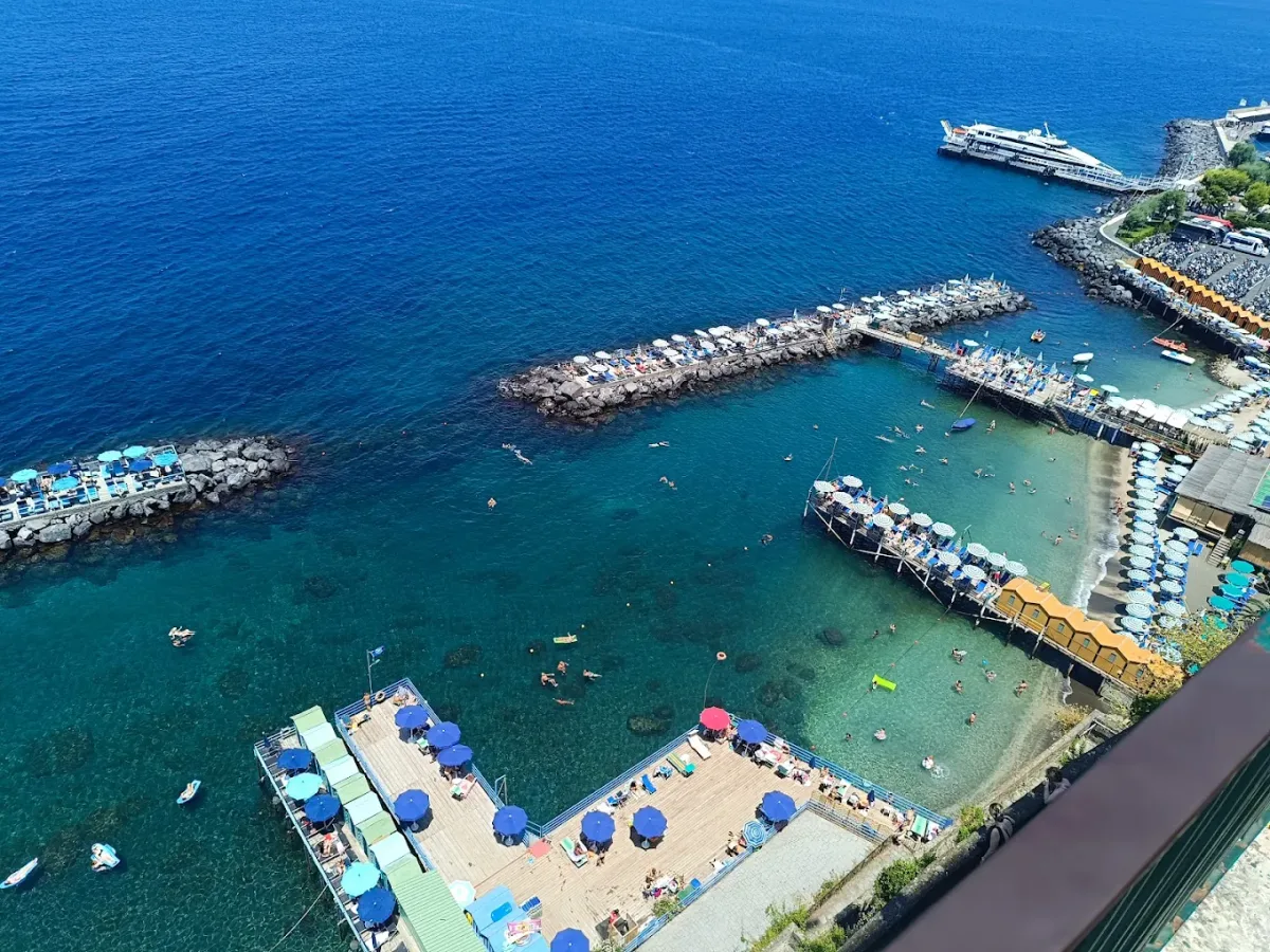 Turquoise and white umbrellas on the wooden piers at Peter's Beach, Marina Piccola