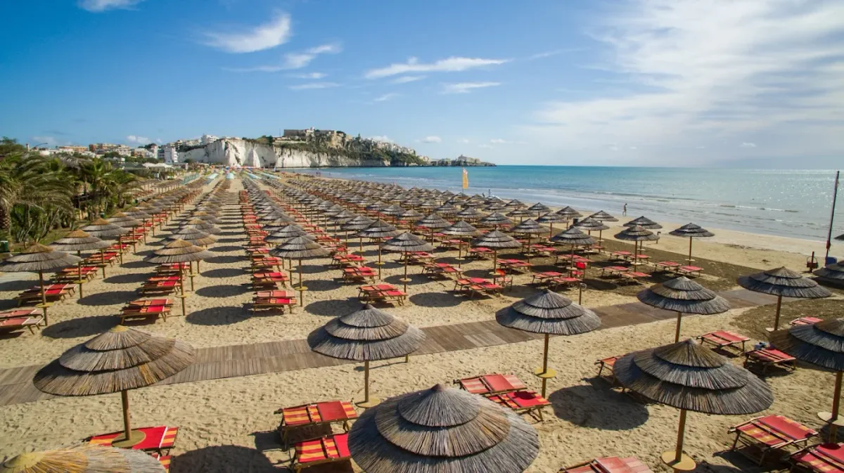 Straw umbrellas and white loungers on the sand at Pelikano, Scialara beach